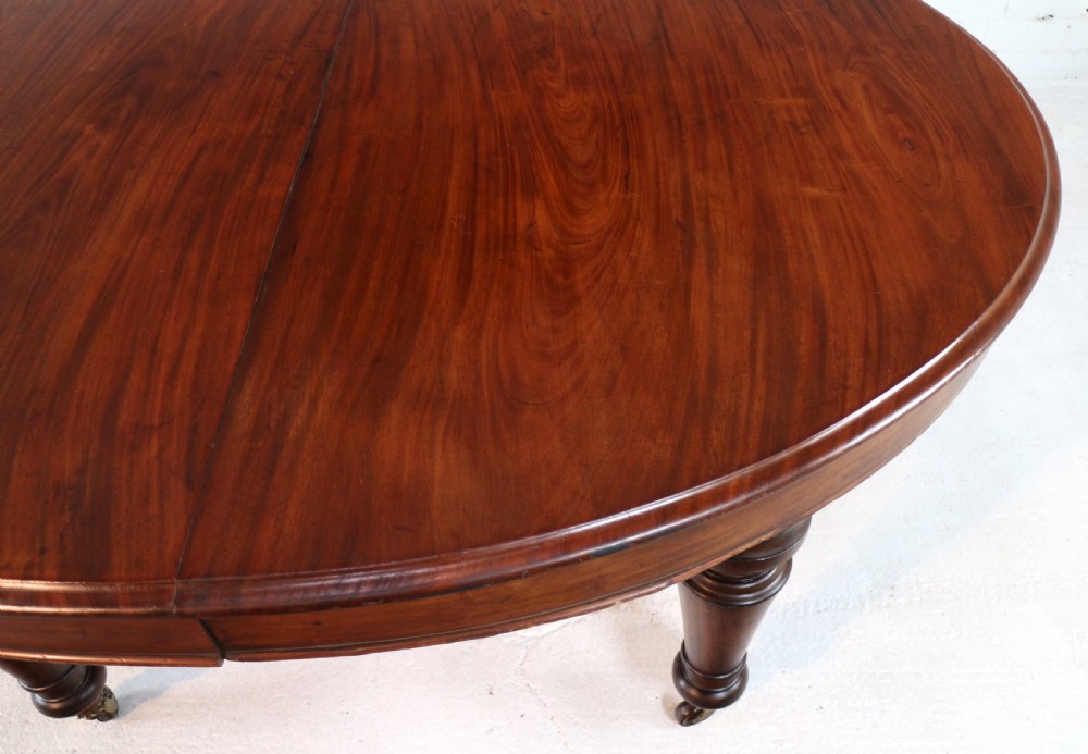 An extended Victorian Cuban mahogany dining table with rounded ends, turned legs, and brass castors. View XXVI
