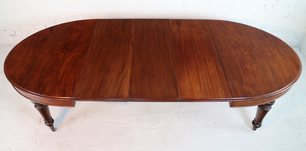 An extended Victorian Cuban mahogany dining table with rounded ends, turned legs, and brass castors. View XXIX