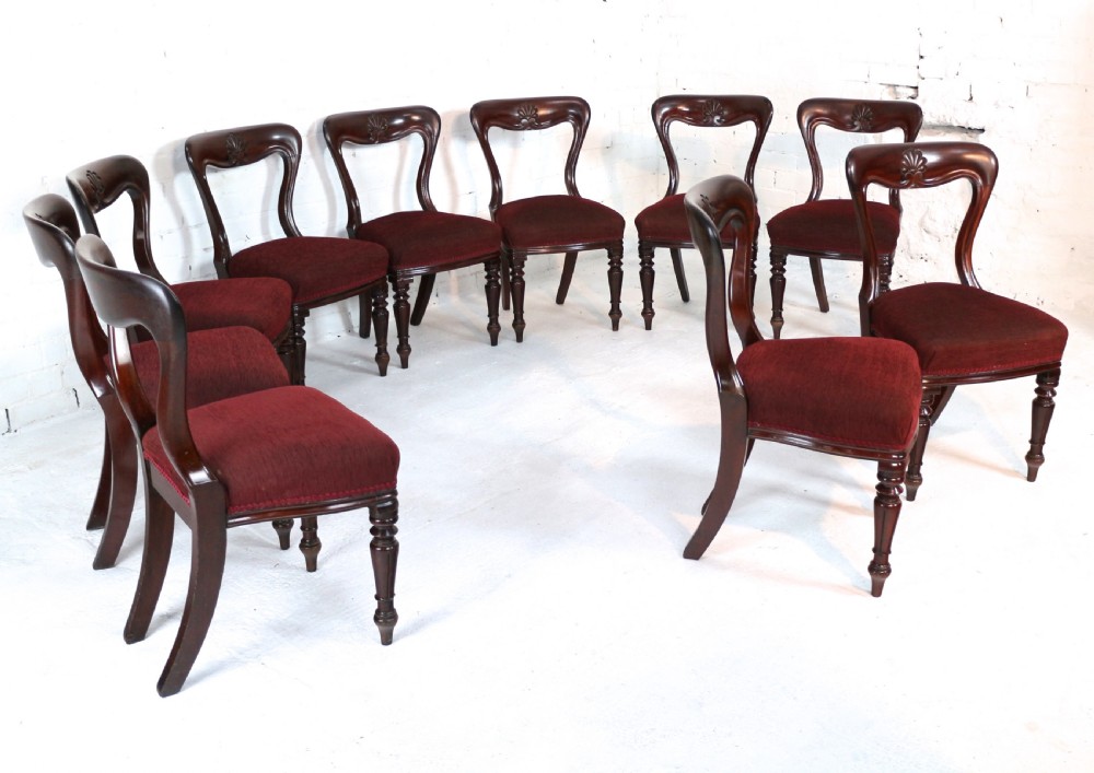 A set of ten William IV mahogany dining chairs with carved top rails, turned front legs, and deep red upholstery. View III