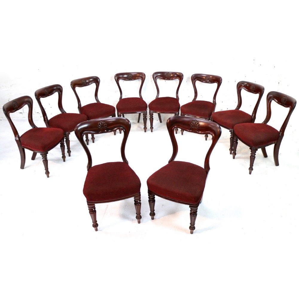 A set of ten William IV mahogany dining chairs with carved top rails, turned front legs, and deep red upholstery. View IV