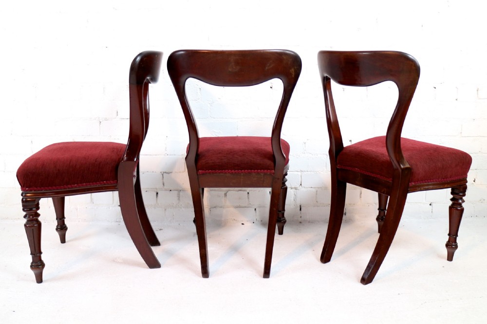 A set of ten William IV mahogany dining chairs with carved top rails, turned front legs, and deep red upholstery. View V