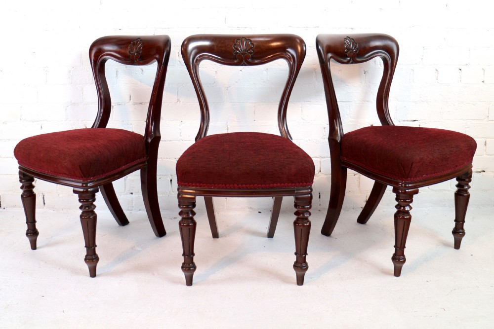 A set of ten William IV mahogany dining chairs with carved top rails, turned front legs, and deep red upholstery. View VI
