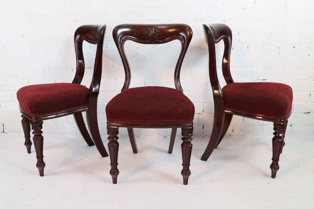 A set of ten William IV mahogany dining chairs with carved top rails, turned front legs, and deep red upholstery. View VII