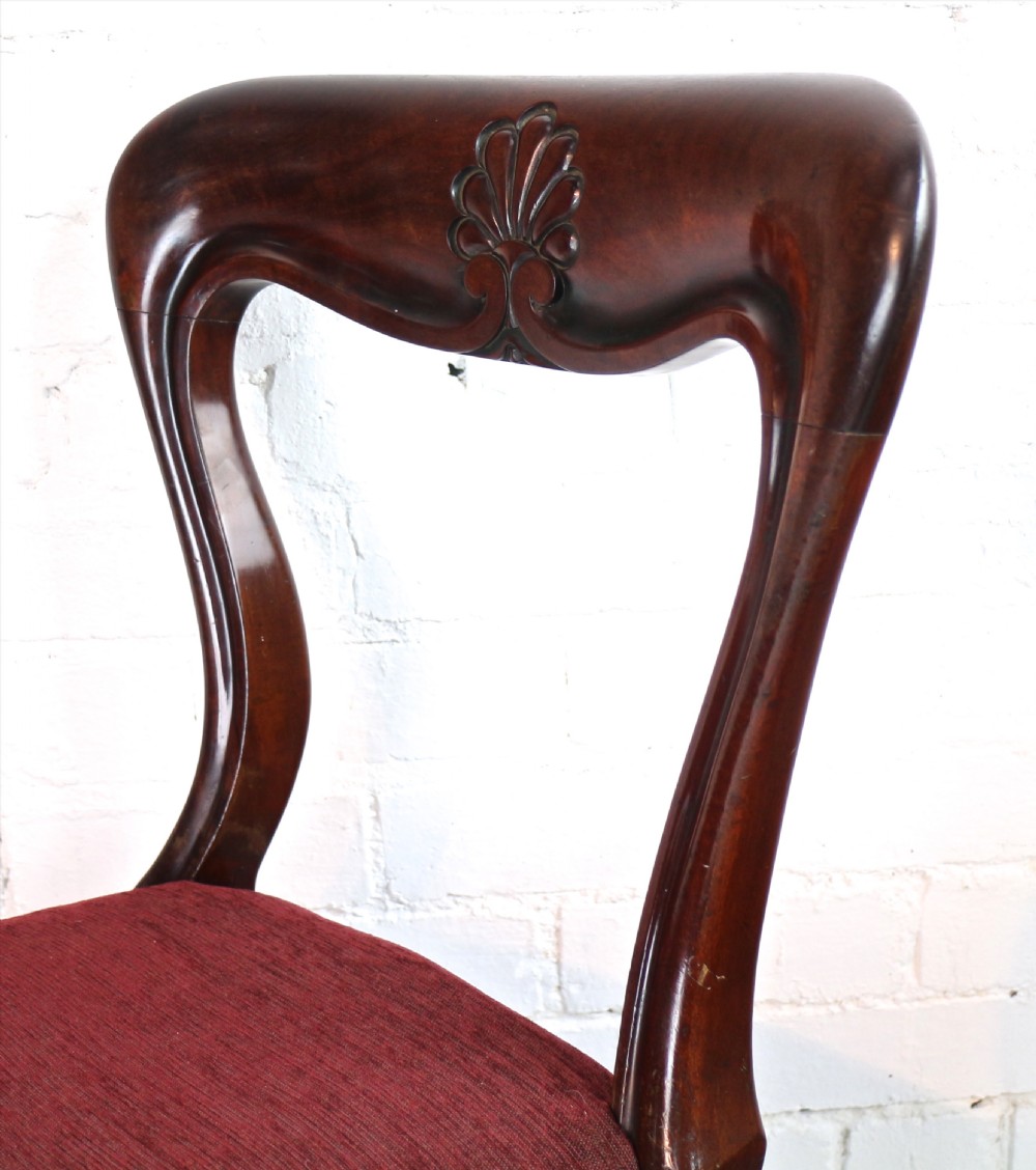 A set of ten William IV mahogany dining chairs with carved top rails, turned front legs, and deep red upholstery. View XII