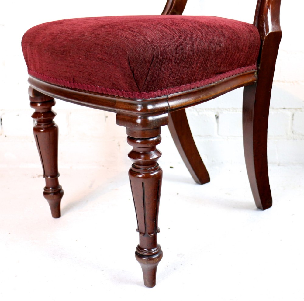 A set of ten William IV mahogany dining chairs with carved top rails, turned front legs, and deep red upholstery. View XV