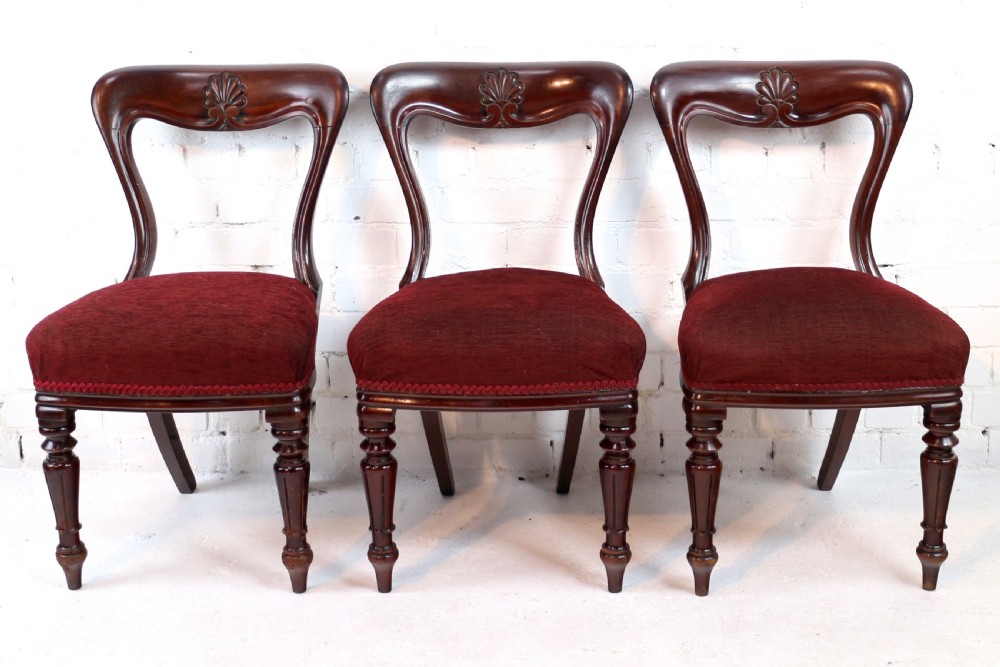 A set of ten William IV mahogany dining chairs with carved top rails, turned front legs, and deep red upholstery. View XVI