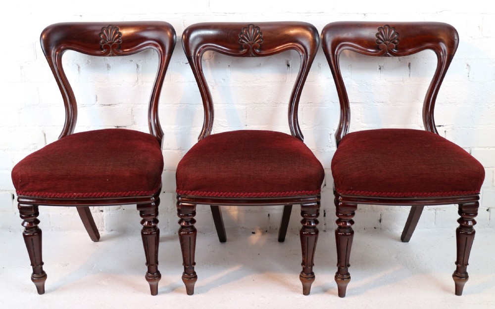 A set of ten William IV mahogany dining chairs with carved top rails, turned front legs, and deep red upholstery. View XX