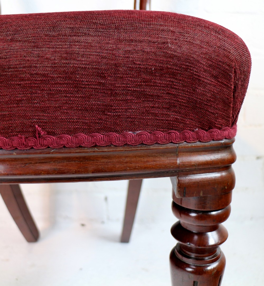 A set of ten William IV mahogany dining chairs with carved top rails, turned front legs, and deep red upholstery. View XXIII