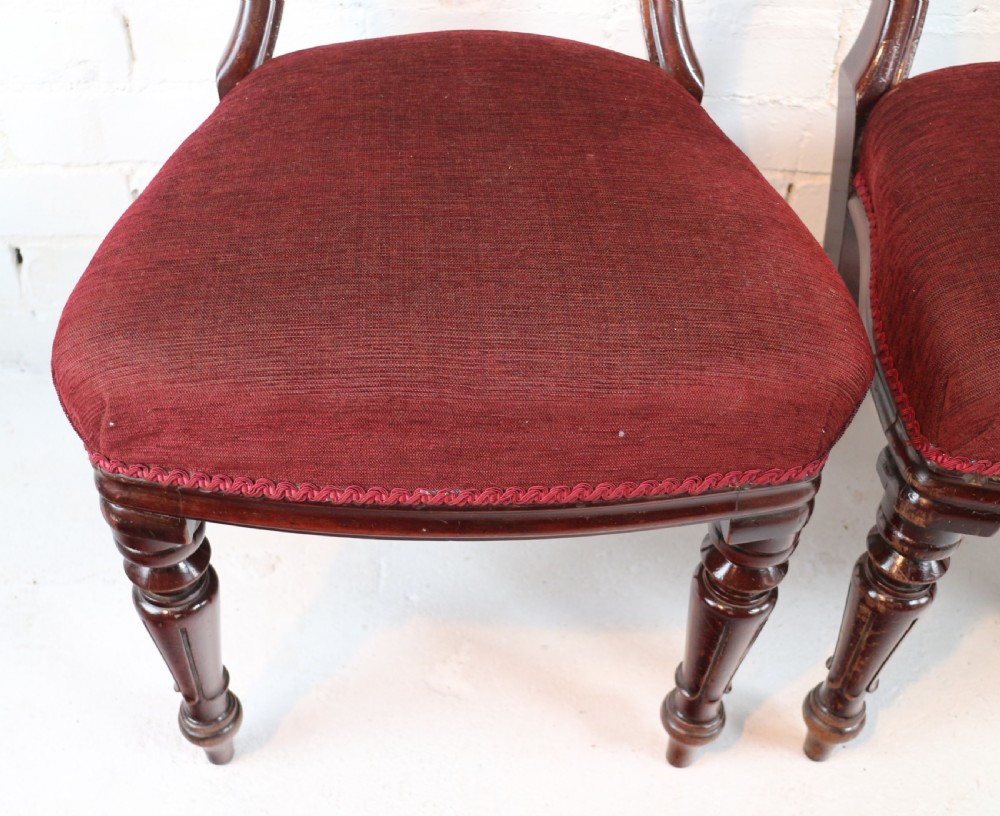 A set of ten William IV mahogany dining chairs with carved top rails, turned front legs, and deep red upholstery. View XXV