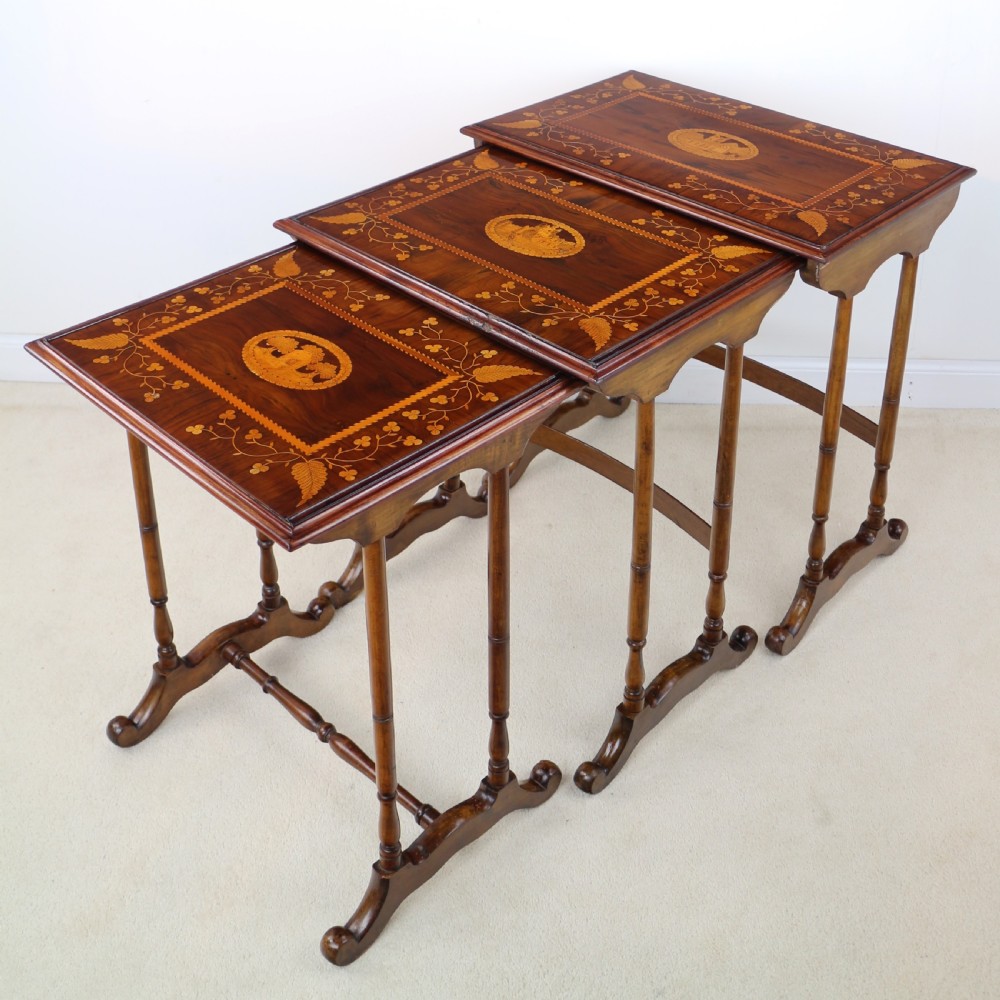 A set of three nested wooden side tables featuring detailed marquetry inlays of foliage and central vignettes, supported by slender turned legs and scroll feet. View II