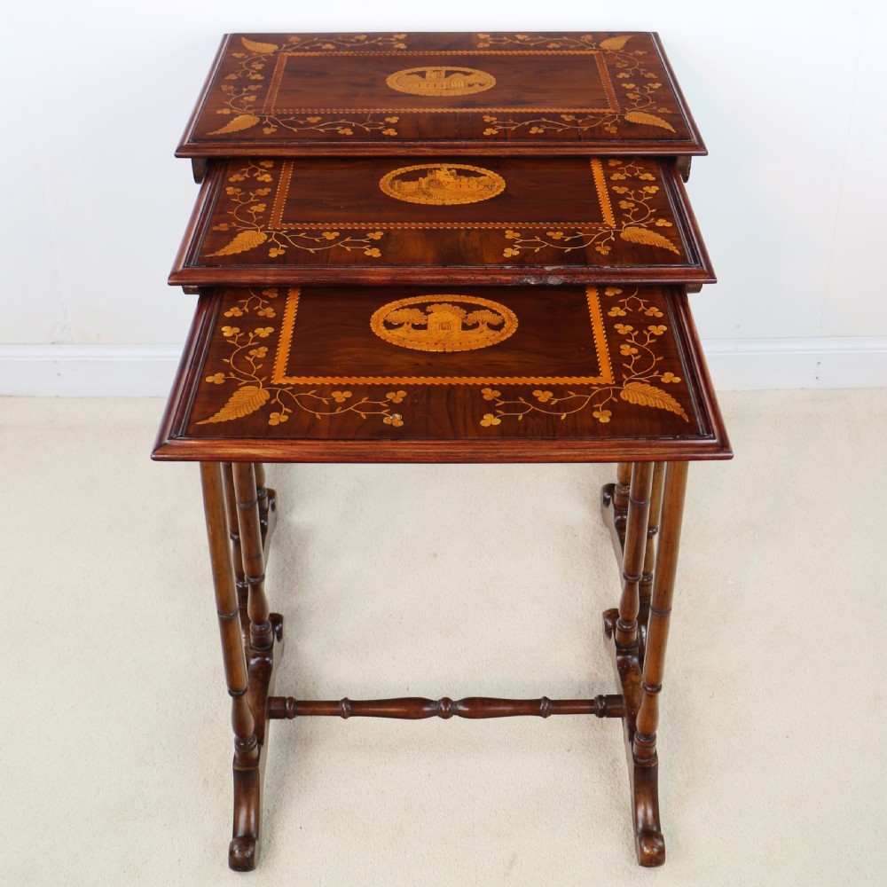 A set of three nested wooden side tables featuring detailed marquetry inlays of foliage and central vignettes, supported by slender turned legs and scroll feet. View III