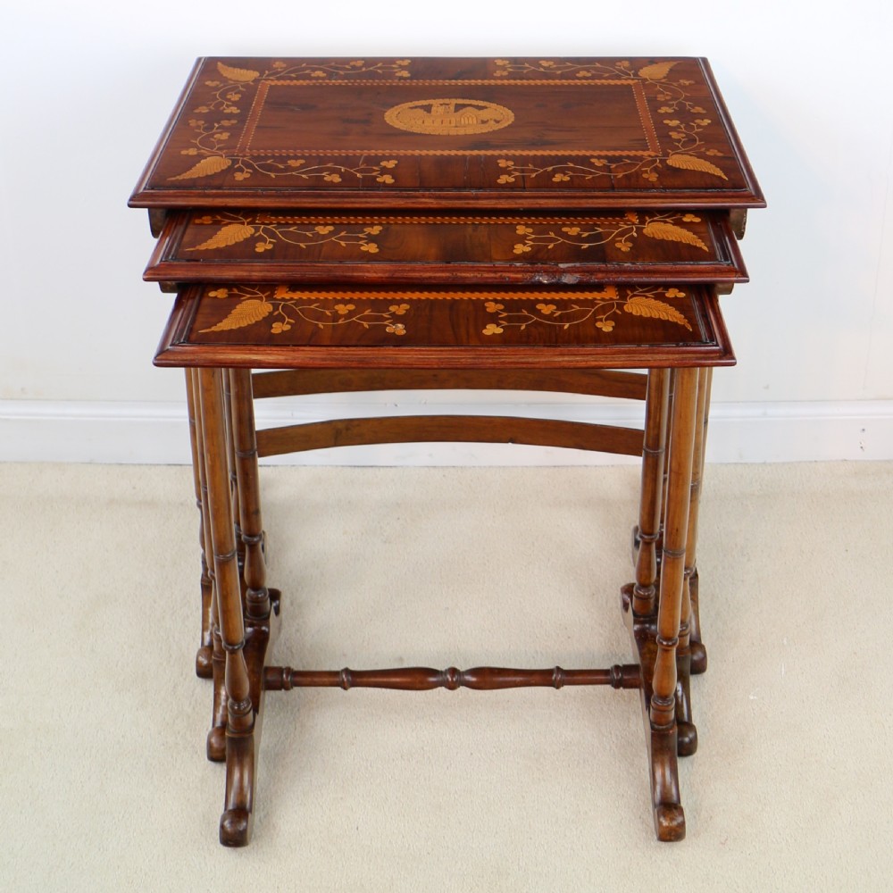 A set of three nested wooden side tables featuring detailed marquetry inlays of foliage and central vignettes, supported by slender turned legs and scroll feet. View V