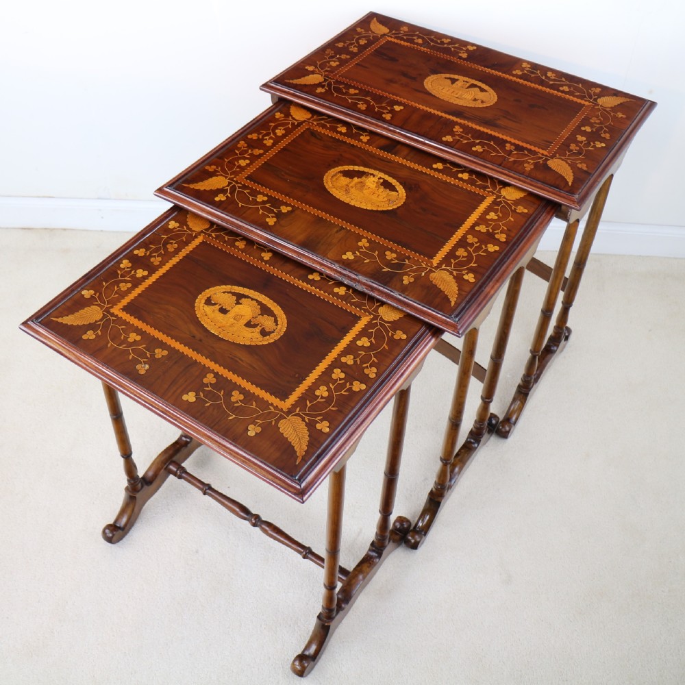 A set of three nested wooden side tables featuring detailed marquetry inlays of foliage and central vignettes, supported by slender turned legs and scroll feet. View VII