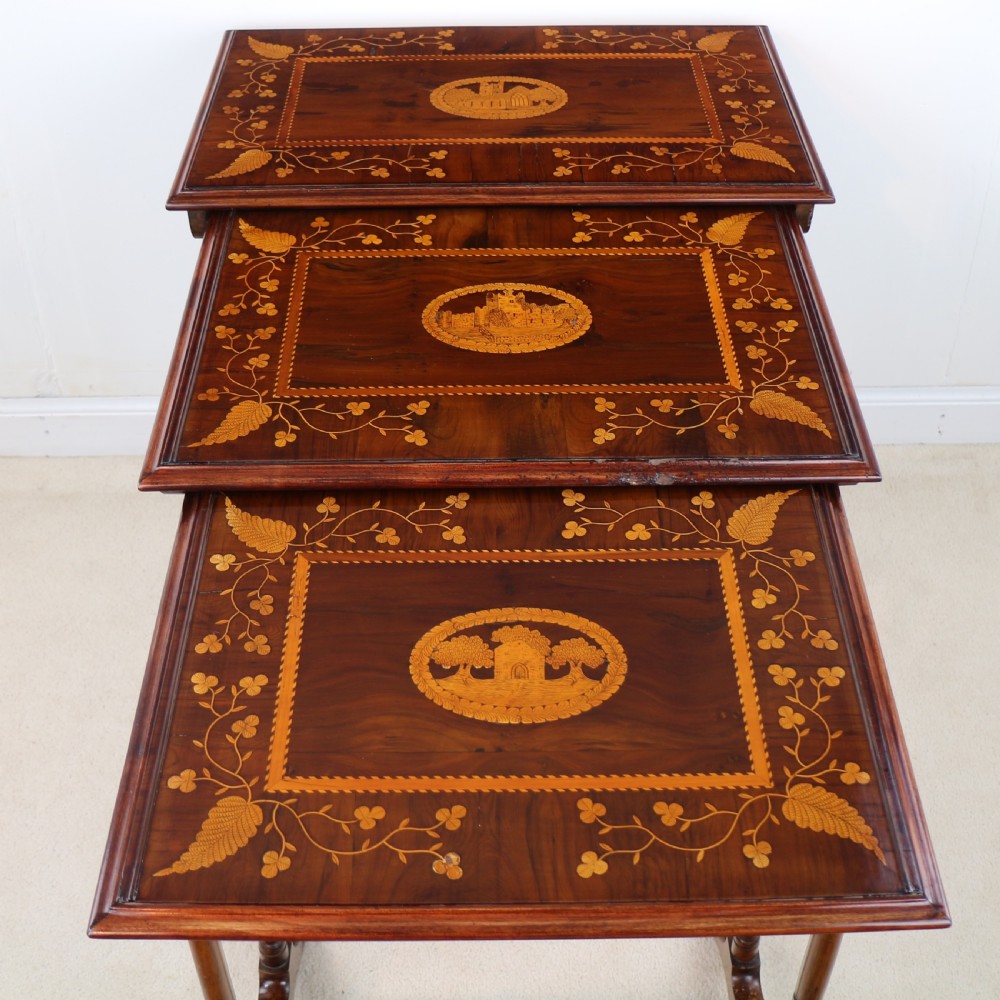 A set of three nested wooden side tables featuring detailed marquetry inlays of foliage and central vignettes, supported by slender turned legs and scroll feet. View XI