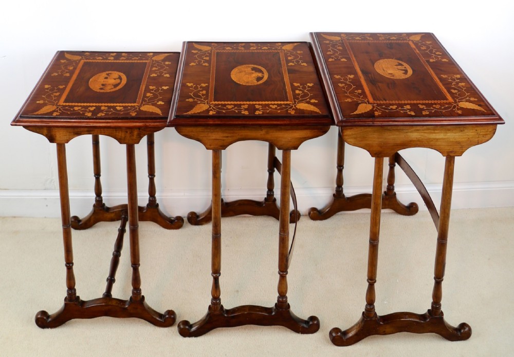 A set of three nested wooden side tables featuring detailed marquetry inlays of foliage and central vignettes, supported by slender turned legs and scroll feet. View XII