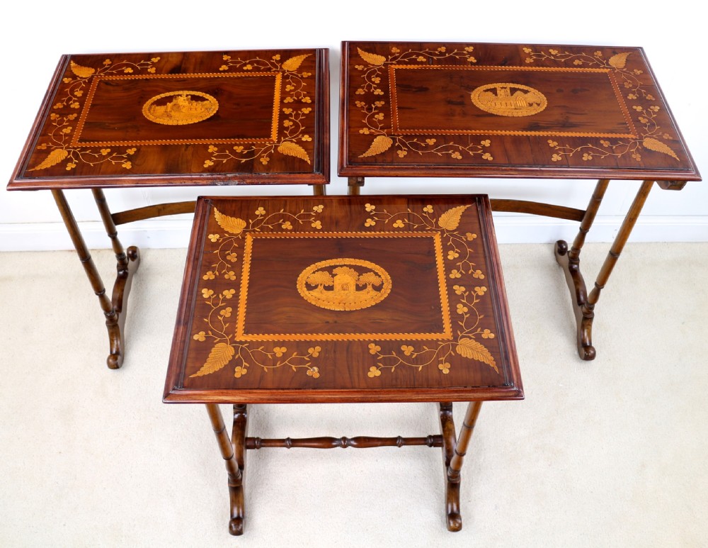 A set of three nested wooden side tables featuring detailed marquetry inlays of foliage and central vignettes, supported by slender turned legs and scroll feet. View XIV