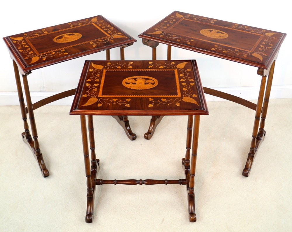 A set of three nested wooden side tables featuring detailed marquetry inlays of foliage and central vignettes, supported by slender turned legs and scroll feet. View XXI