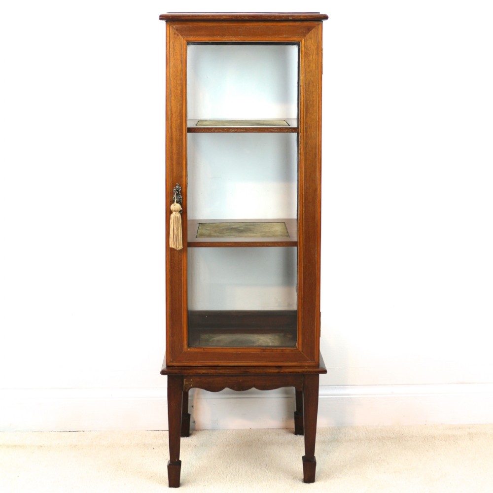 A tall Edwardian mahogany glazed bijouterie cabinet featuring glass panels on all sides, two interior shelves, square tapered legs, and satinwood crossbanding. View II