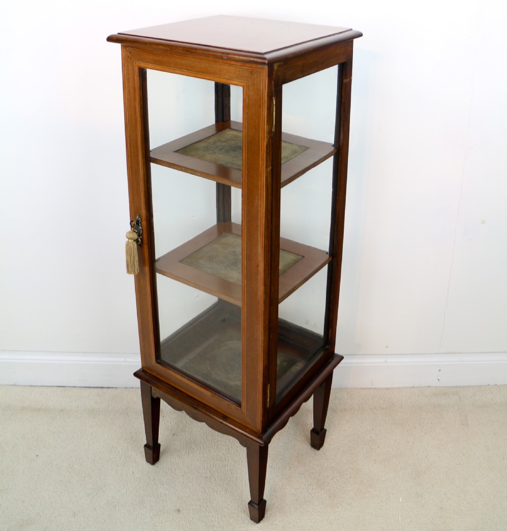 A tall Edwardian mahogany glazed bijouterie cabinet featuring glass panels on all sides, two interior shelves, square tapered legs, and satinwood crossbanding. View III