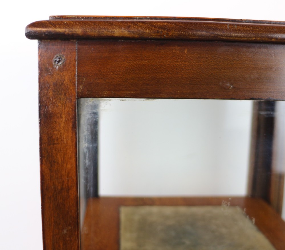 A tall Edwardian mahogany glazed bijouterie cabinet featuring glass panels on all sides, two interior shelves, square tapered legs, and satinwood crossbanding. View XXII