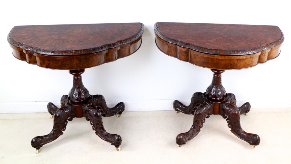 A pair of Victorian burr walnut fold-over card tables featuring shaped demi-lune tops, carved aprons, central turned pedestals, and carved quadform legs with castors. View III