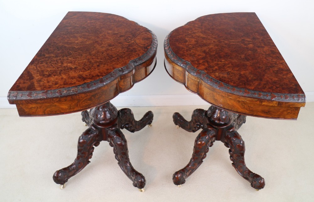 A pair of Victorian burr walnut fold-over card tables featuring shaped demi-lune tops, carved aprons, central turned pedestals, and carved quadform legs with castors. View VIII