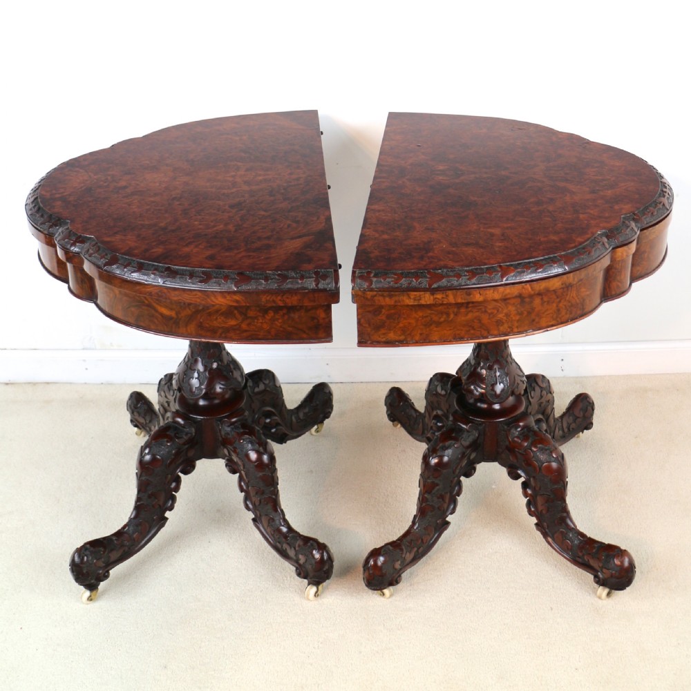A pair of Victorian burr walnut fold-over card tables featuring shaped demi-lune tops, carved aprons, central turned pedestals, and carved quadform legs with castors. View IX