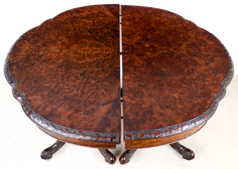 A pair of Victorian burr walnut fold-over card tables featuring shaped demi-lune tops, carved aprons, central turned pedestals, and carved quadform legs with castors. View XI