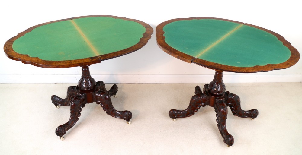 A pair of Victorian burr walnut fold-over card tables featuring shaped demi-lune tops, carved aprons, central turned pedestals, and carved quadform legs with castors. View XVIII