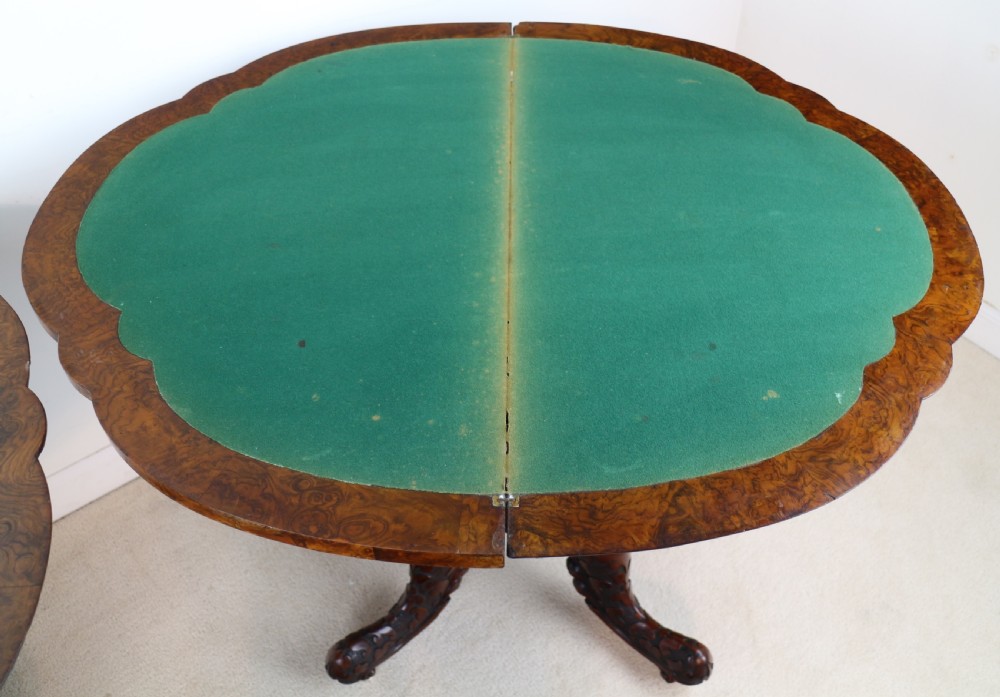A pair of Victorian burr walnut fold-over card tables featuring shaped demi-lune tops, carved aprons, central turned pedestals, and carved quadform legs with castors. View XXIX
