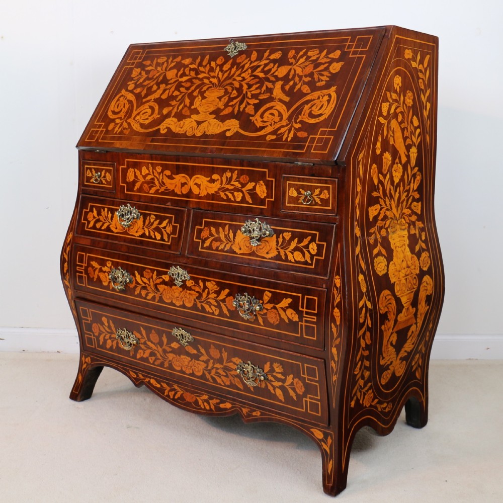 A 19th-century Dutch walnut bombe bureau decorated with intricate floral marquetry, featuring a slant front and curved drawers with brass handles.