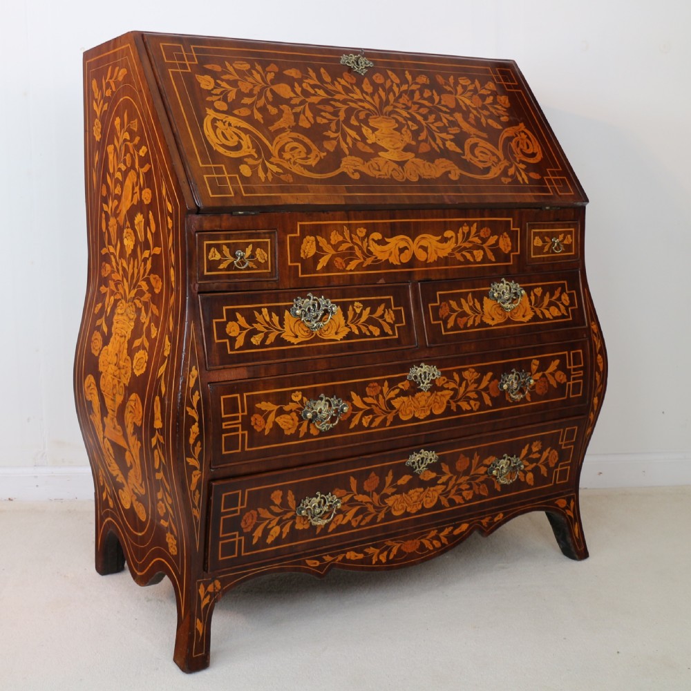 A 19th-century Dutch walnut bombe bureau decorated with intricate floral marquetry, featuring a slant front and curved drawers with brass handles. View II
