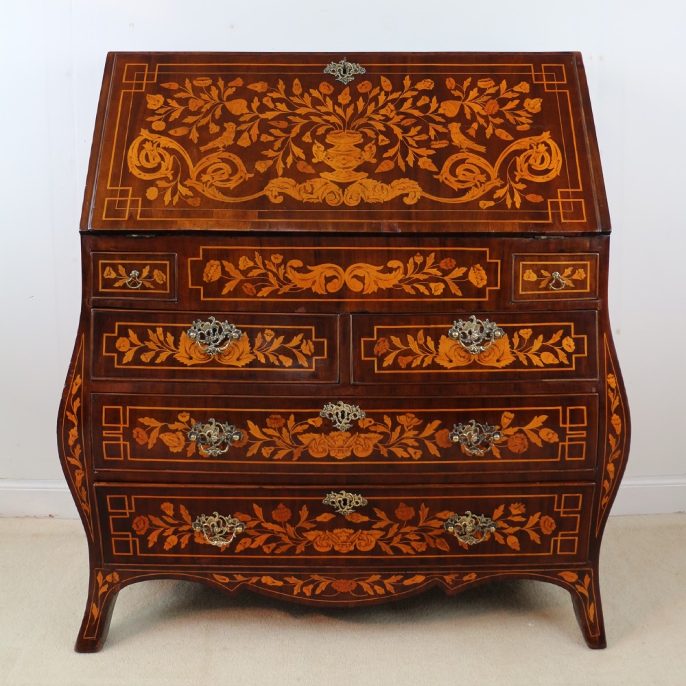 A 19th-century Dutch walnut bombe bureau decorated with intricate floral marquetry, featuring a slant front and curved drawers with brass handles. View III