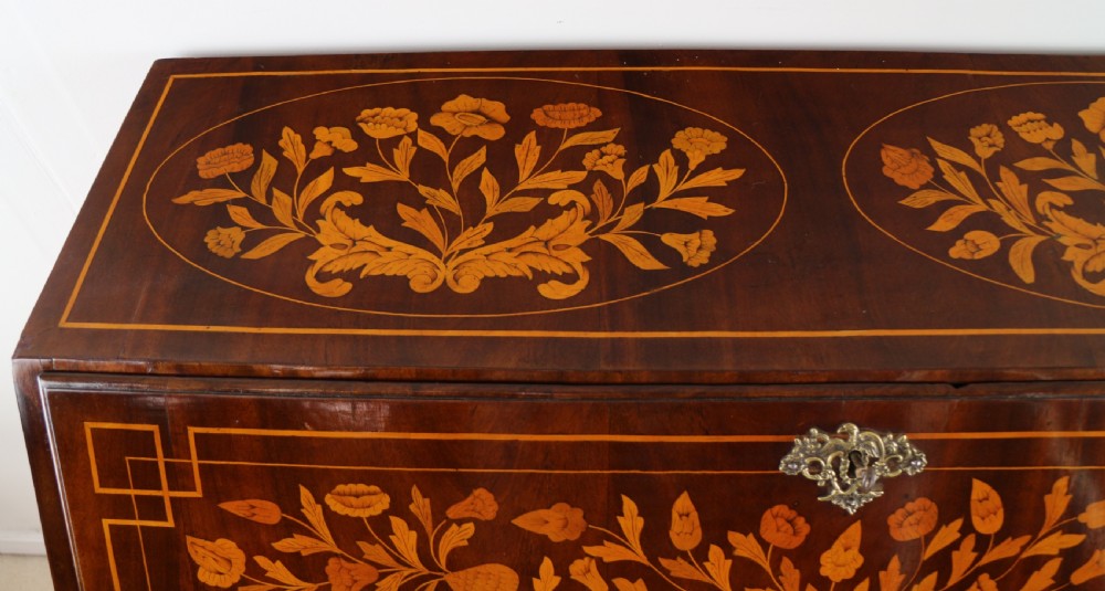 A 19th-century Dutch walnut bombe bureau decorated with intricate floral marquetry, featuring a slant front and curved drawers with brass handles. View VIII