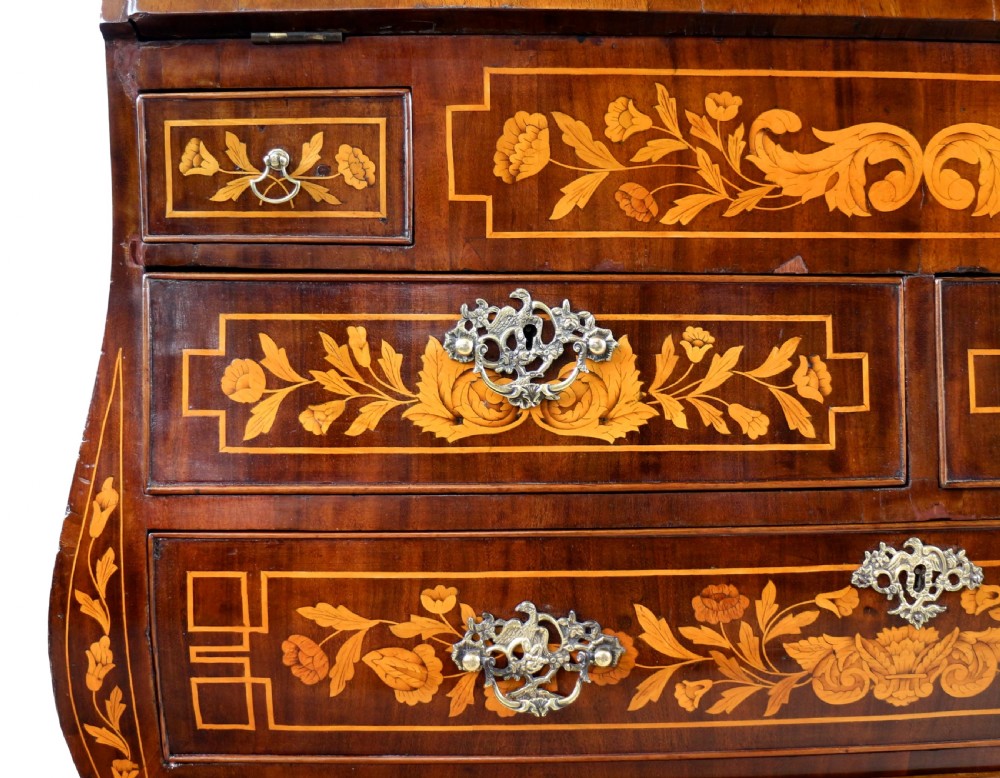 A 19th-century Dutch walnut bombe bureau decorated with intricate floral marquetry, featuring a slant front and curved drawers with brass handles. View XI