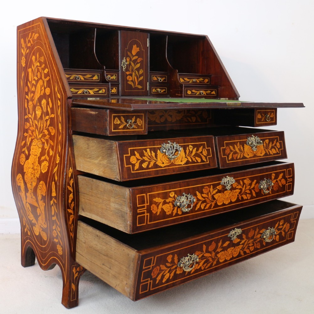 A 19th-century Dutch walnut bombe bureau decorated with intricate floral marquetry, featuring a slant front and curved drawers with brass handles. View XV