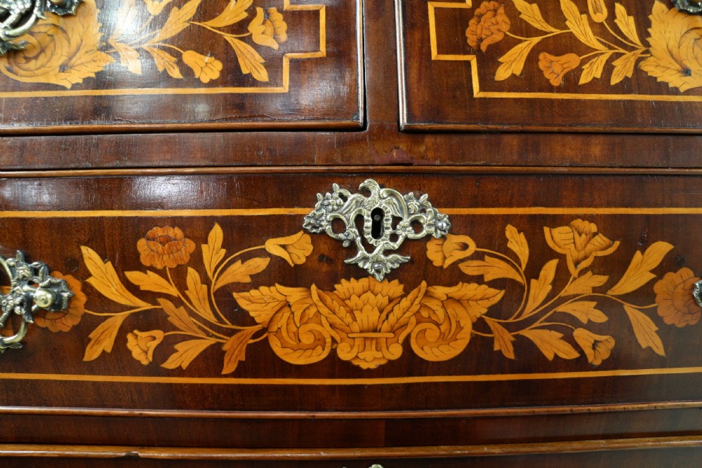 A 19th-century Dutch walnut bombe bureau decorated with intricate floral marquetry, featuring a slant front and curved drawers with brass handles. View XVI