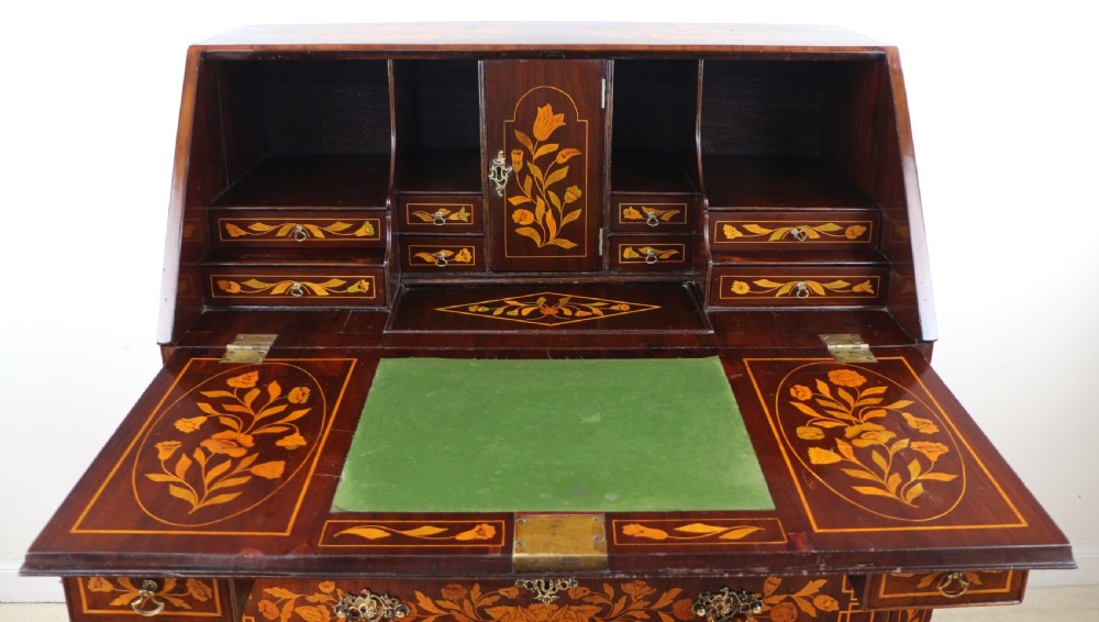 A 19th-century Dutch walnut bombe bureau decorated with intricate floral marquetry, featuring a slant front and curved drawers with brass handles. View XIX