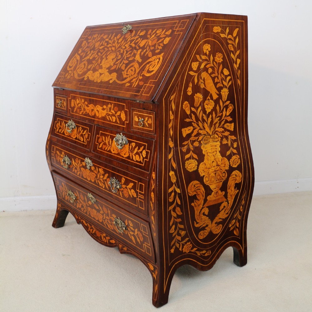A 19th-century Dutch walnut bombe bureau decorated with intricate floral marquetry, featuring a slant front and curved drawers with brass handles. View XXII
