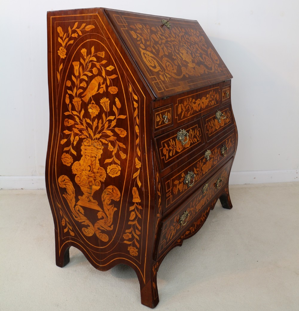 A 19th-century Dutch walnut bombe bureau decorated with intricate floral marquetry, featuring a slant front and curved drawers with brass handles. View XXV