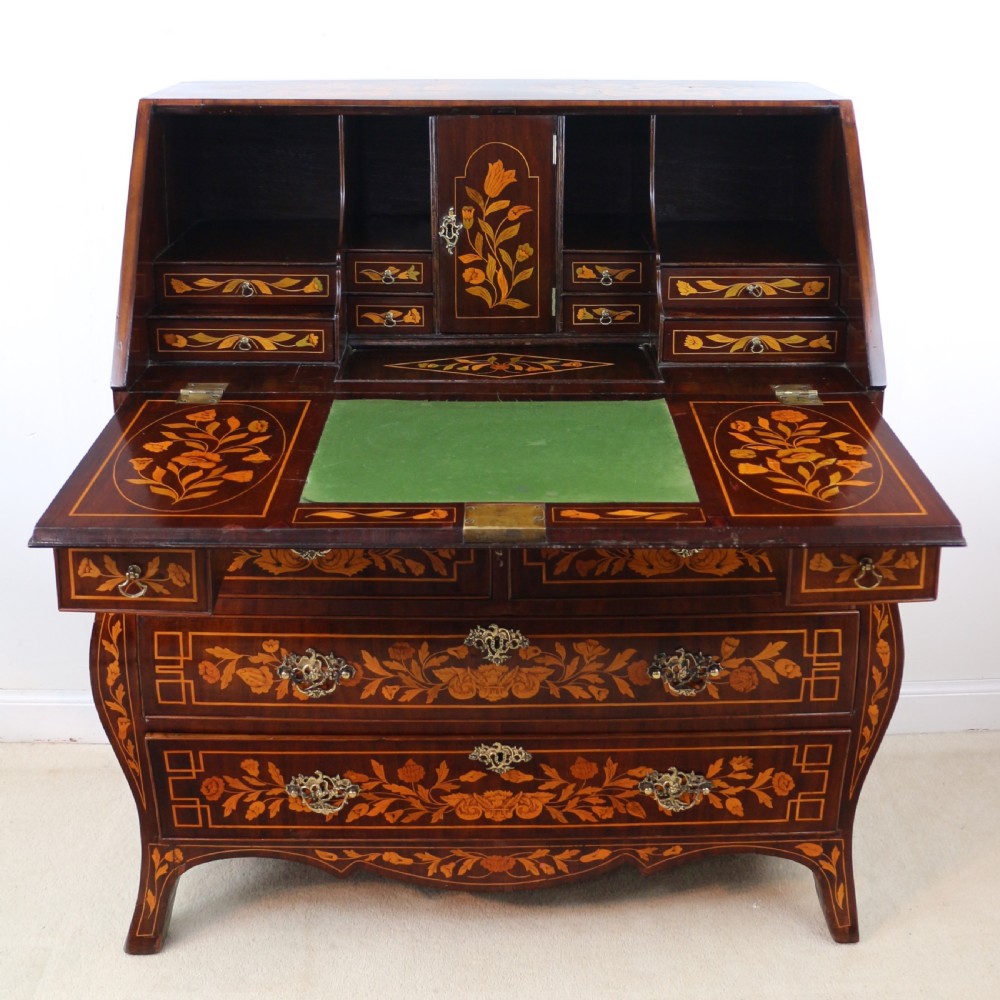 A 19th-century Dutch walnut bombe bureau decorated with intricate floral marquetry, featuring a slant front and curved drawers with brass handles. View XXVI