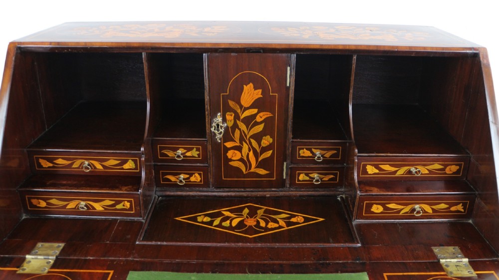 A 19th-century Dutch walnut bombe bureau decorated with intricate floral marquetry, featuring a slant front and curved drawers with brass handles. View XXX