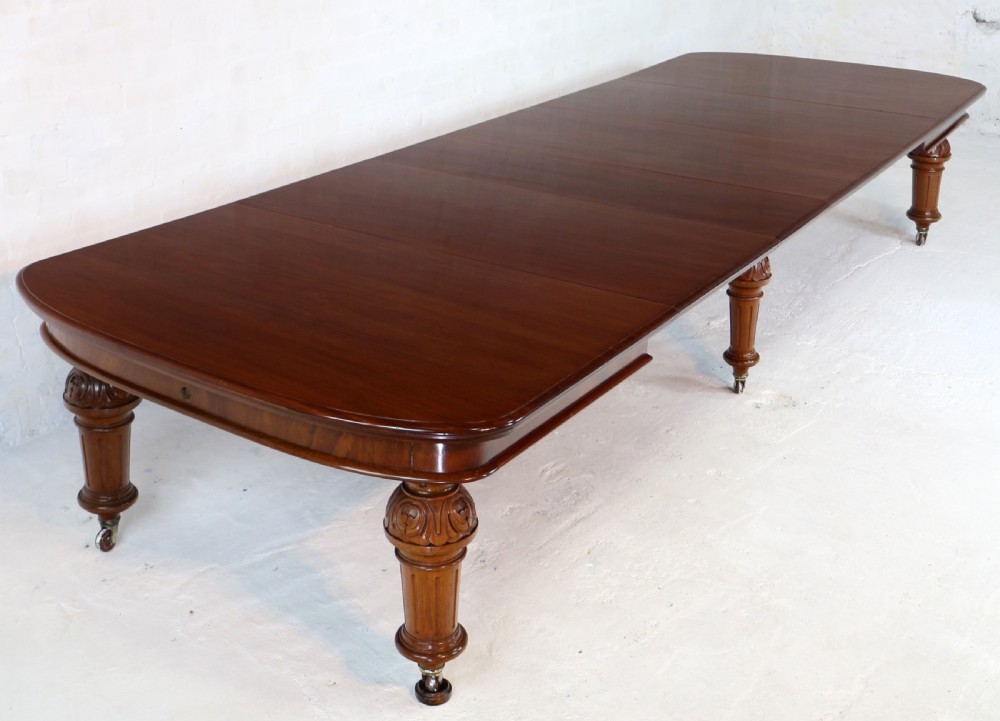 A large Victorian mahogany extending dining table featuring six turned carved legs fitted with brass castors and four removable leaf inserts. View V