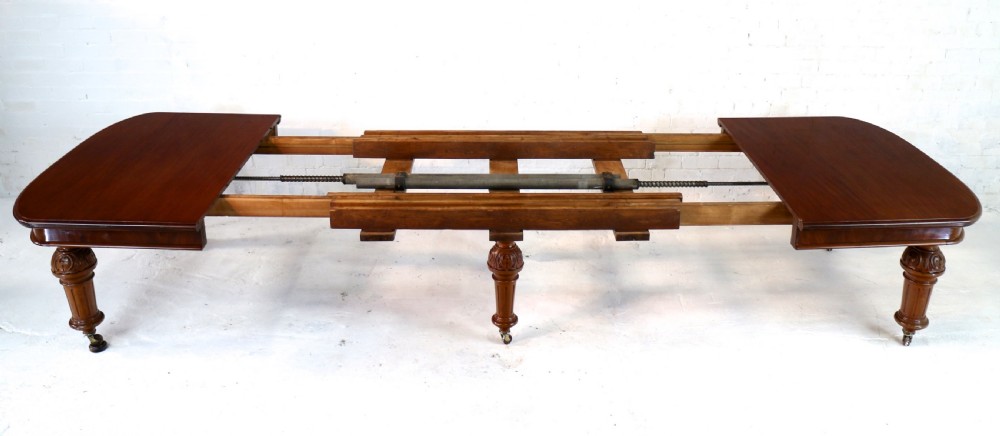 A large Victorian mahogany extending dining table featuring six turned carved legs fitted with brass castors and four removable leaf inserts. View XIII