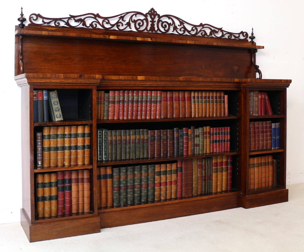 An antique Regency open rosewood bookcase featuring an inverted breakfront profile, multi-tier shelving, and an intricately carved fretwork gallery. View III