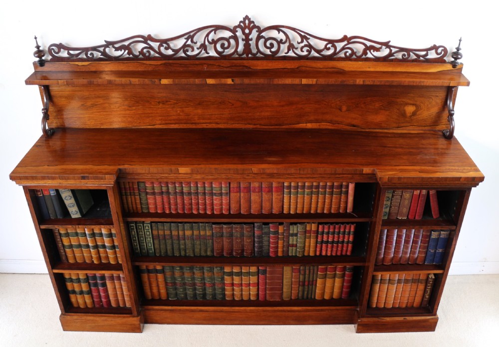 An antique Regency open rosewood bookcase featuring an inverted breakfront profile, multi-tier shelving, and an intricately carved fretwork gallery. View X