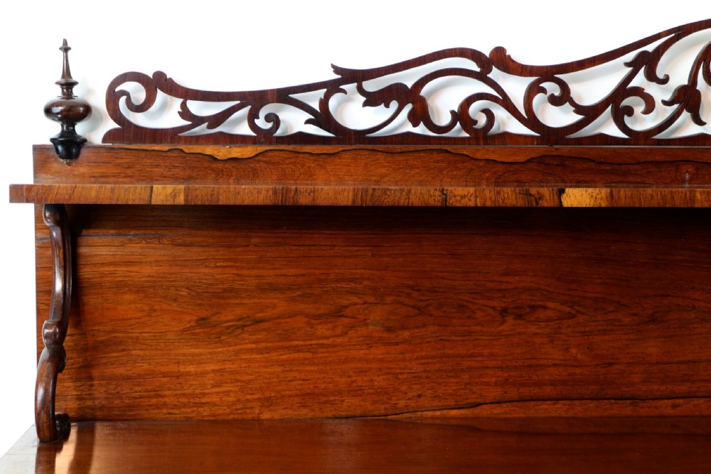 An antique Regency open rosewood bookcase featuring an inverted breakfront profile, multi-tier shelving, and an intricately carved fretwork gallery. View XI