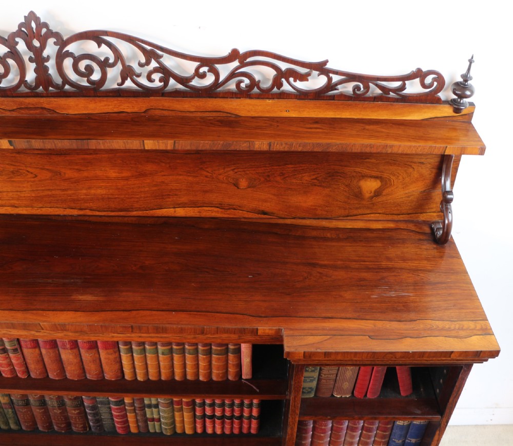 An antique Regency open rosewood bookcase featuring an inverted breakfront profile, multi-tier shelving, and an intricately carved fretwork gallery. View XV