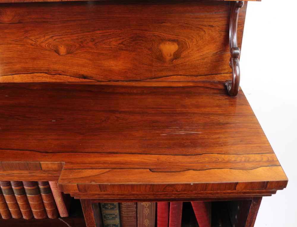 An antique Regency open rosewood bookcase featuring an inverted breakfront profile, multi-tier shelving, and an intricately carved fretwork gallery. View XVI