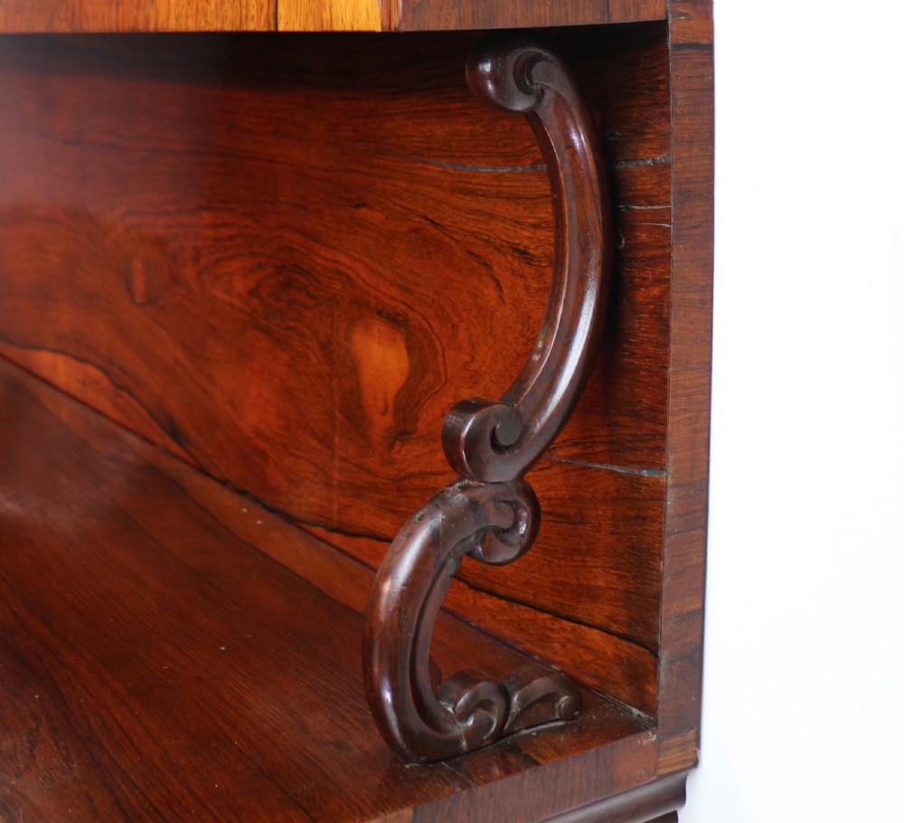 An antique Regency open rosewood bookcase featuring an inverted breakfront profile, multi-tier shelving, and an intricately carved fretwork gallery. View XVII